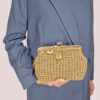 Donna con completo blu che tiene in mano borsa oro con chiusura clic clac, lavorata all'uncinetto.