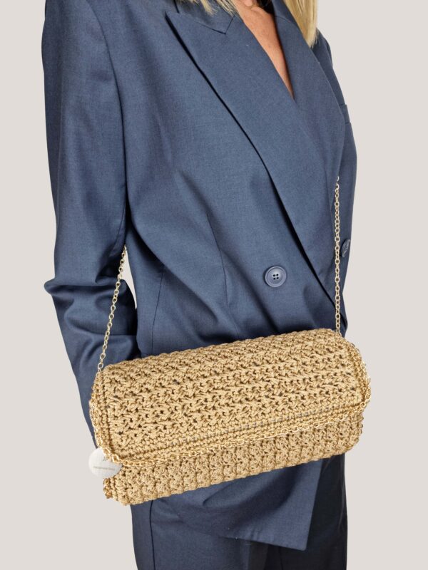 Donna in completo blu con borsa a tracolla oro, lavorata all'uncinetto.