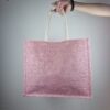 Ragazza con borsa a spalla in tela rosa, con decorazioni rosa, lavorate all'uncinetto