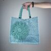 Ragazza con borsa a spalla in tela verde acqua, con decorazioni verde acqua, lavorate all'uncinetto